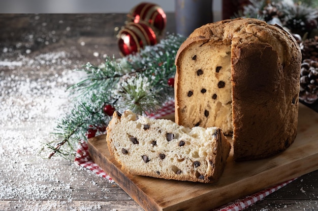 Panettone tradicional navideño con corbata roja y adornos navideños en mesa de madera