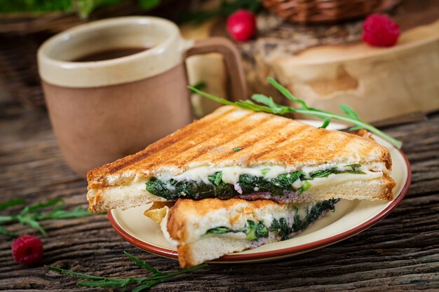 Panini sandwich con queso y hojas de mostaza. Cafe mañanero. Desayuno del pueblo