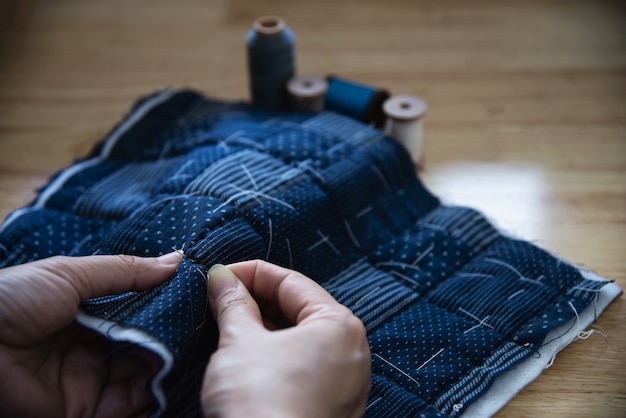 Paño de costura de mujer vintage a mano con bordado en mesa de madera - personas y concepto de bricolaje hecho a mano