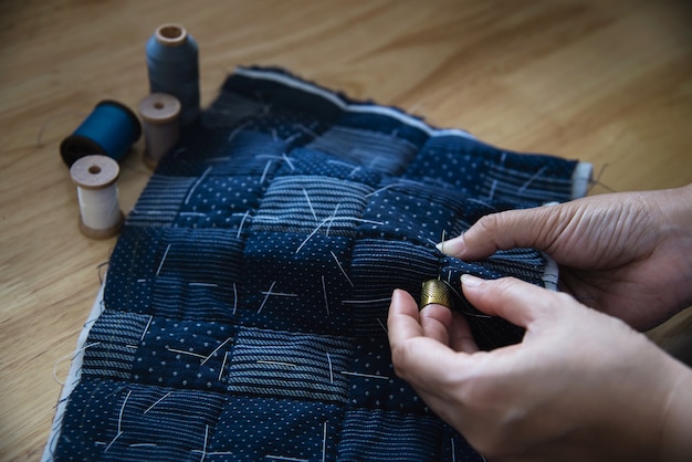Paño de costura de mujer vintage a mano con bordado en mesa de madera - personas y concepto de bricolaje hecho a mano