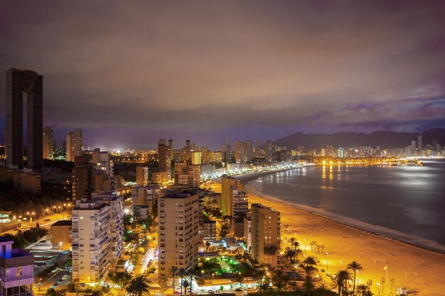 Panorama de la ciudad costera al atardecer con luces reflejadas en el mar