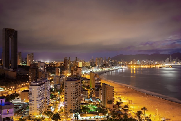 Panorama de la ciudad costera al atardecer con luces reflejadas en el mar