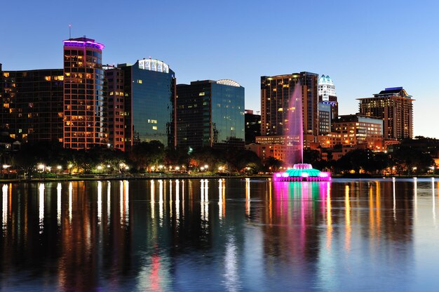 Panorama del horizonte del centro de Orlando sobre el lago Eola al atardecer con rascacielos urbanos y cielo despejado.