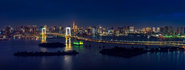 Panorama del paisaje urbano de tokio y el puente del arco iris en la noche.