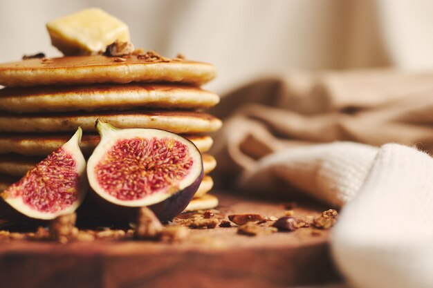 Panqueques con almíbar, mantequilla, higos y nueces tostadas en una placa de madera