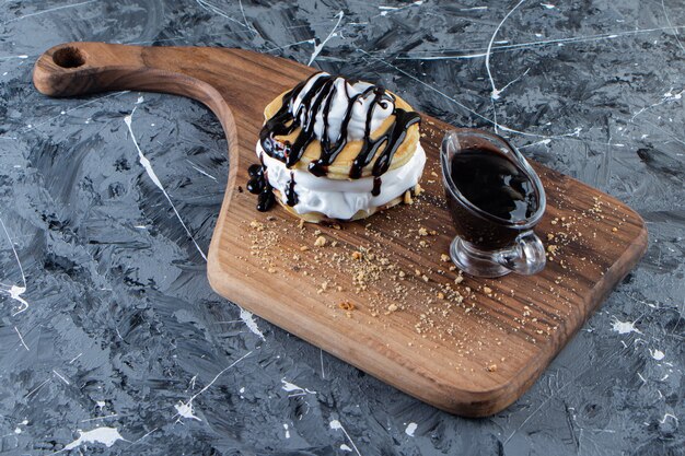 Panqueques con cobertura de chocolate y crema batida sobre tabla de madera.