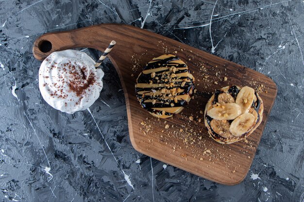 Panqueques con cobertura de plátano y chocolate sobre tabla de madera con delicioso café.