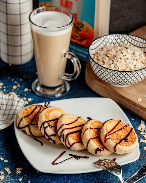 Foto gratuita panqueques cubiertos con jarabe de chocolate y capuchino