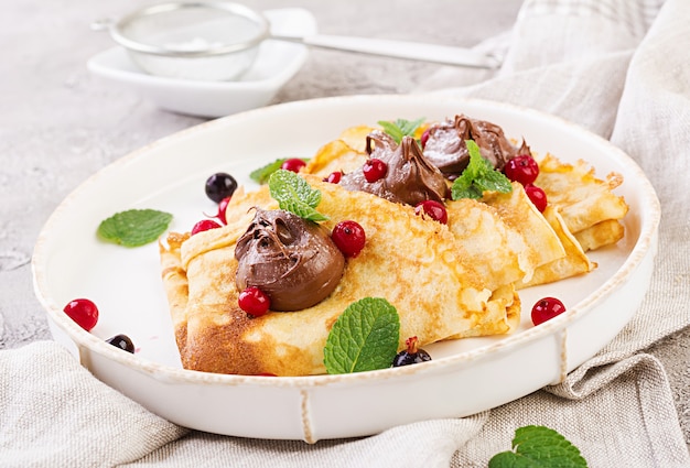 Panqueques con fresas y chocolate decorado con hojas de menta. Desayuno sabroso