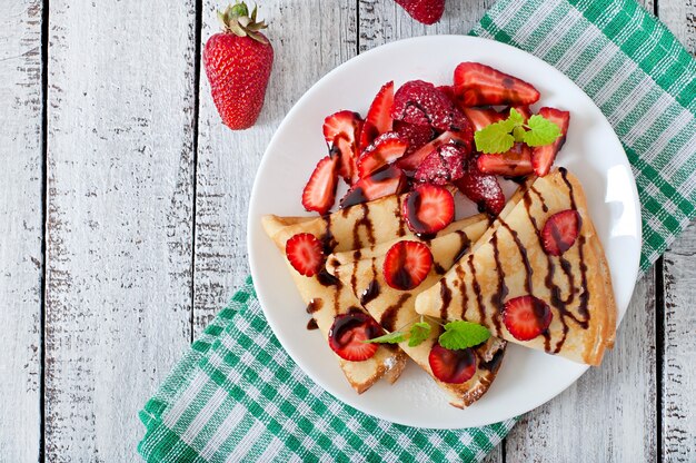 Panqueques con fresas y chocolate decorado con hojas de menta