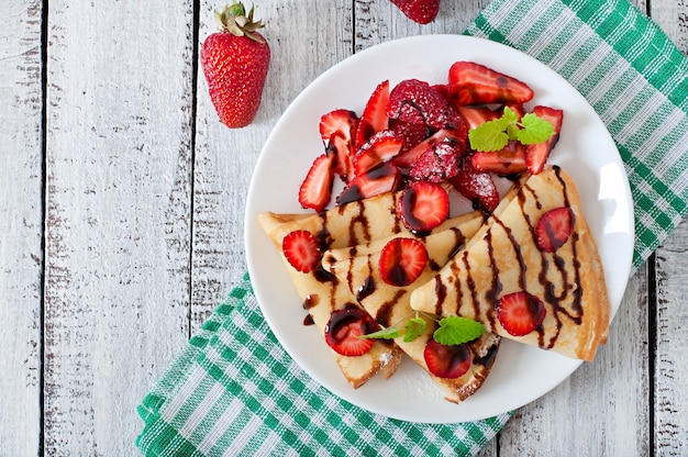 Panqueques con fresas y chocolate decorado con hojas de menta