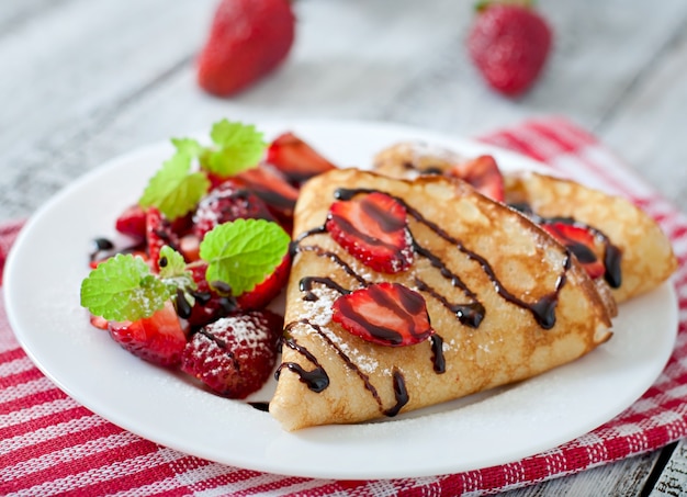 Panqueques con fresas y chocolate decorado con hojas de menta