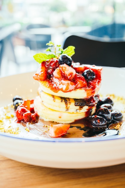 Panqueques con frutas de bayas mixtas en plato blanco