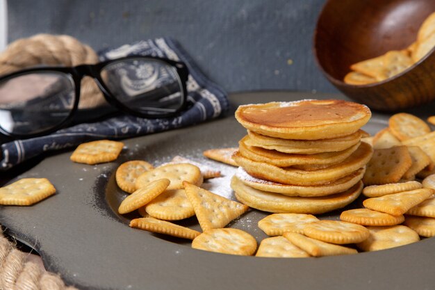 Panqueques y galletas de vista frontal con gafas de sol en gris