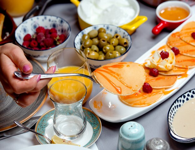 Panqueques con mermelada, aceitunas, un vaso de jugo y frambuesas