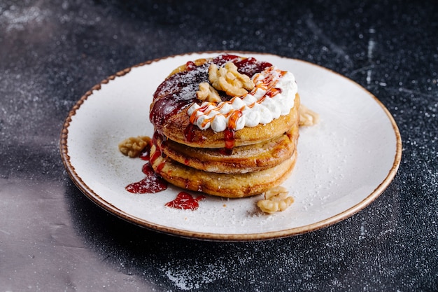 Panqueques con nueces, crema de vainilla y salsa de fresa en la parte superior.