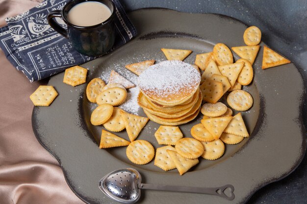 Panqueques de vista frontal y patatas fritas con leche en el escritorio gris