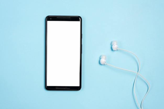 Pantalla blanca en blanco en el teléfono móvil con auriculares contra el fondo azul