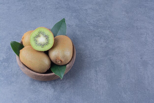 Una pantalla de kiwis en un recipiente sobre una mesa de mármol.