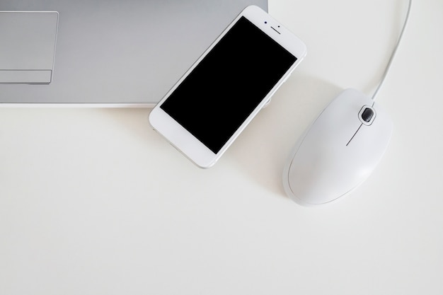 Pantalla móvil en el borde de la computadora portátil con el mouse sobre fondo blanco