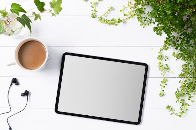 Pantalla de tableta digital en blanco en el fondo de plantas de interior