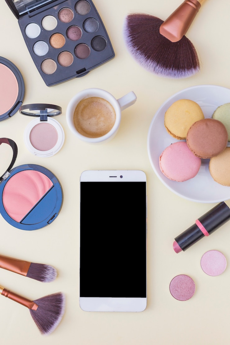 Foto gratuito pantalla del teléfono móvil; café con macarrones y productos cosméticos sobre fondo beige