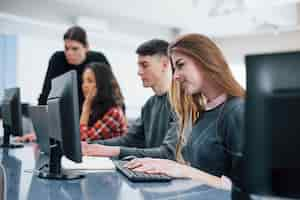 Foto gratuita pantallas de computadora. grupo de jóvenes en ropa casual que trabajan en la oficina moderna