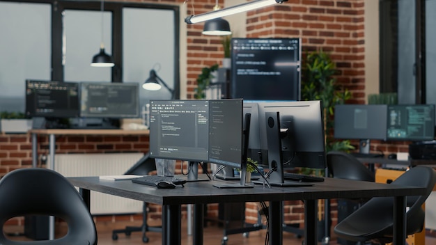 Pantallas de computadora que ejecutan código de programación en la oficina de la agencia de desarrollo de software vacío y computadoras que analizan algoritmos de datos en segundo plano. Servidores de red neuronal cloud computing en sala de datos.