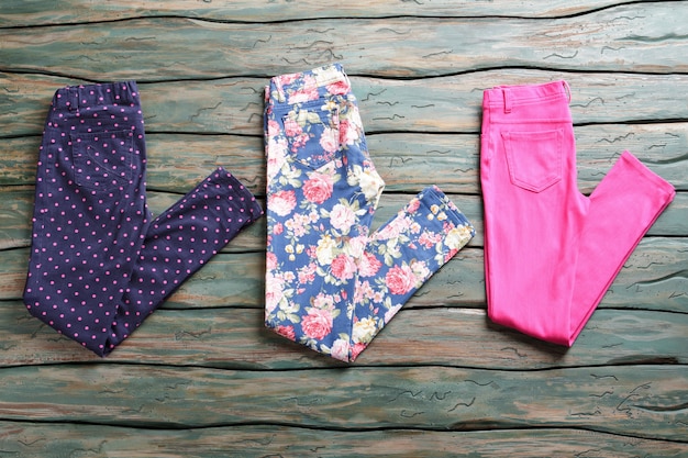 Pantalones doblados sobre fondo de madera. pantalón rosa y azul marino. nuevas prendas de vestir en subasta. no malgastes todo tu dinero.