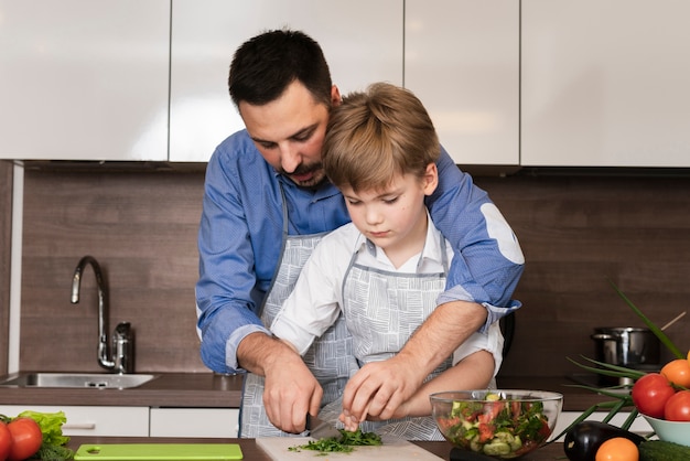 Foto gratuita papá e hijo cortando verduras