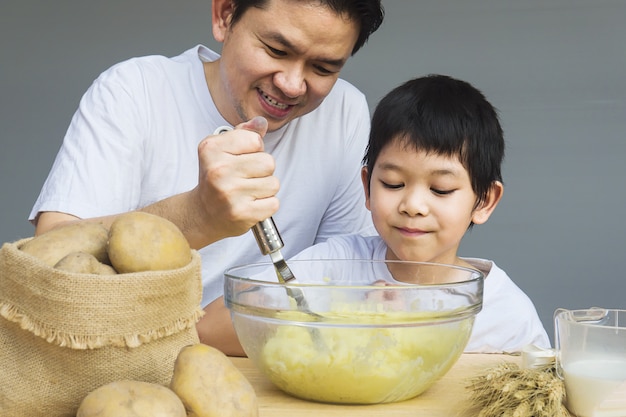 Papá e hijo haciendo puré de papas alegremente