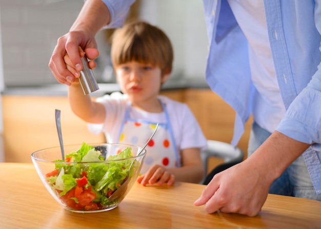 Papá e hijo ponen sal en la ensalada