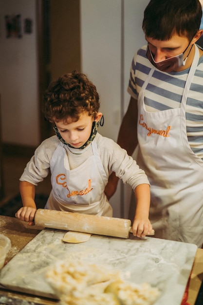 Papá e hijos cocinan pasta en una clase magistral de gastronomía