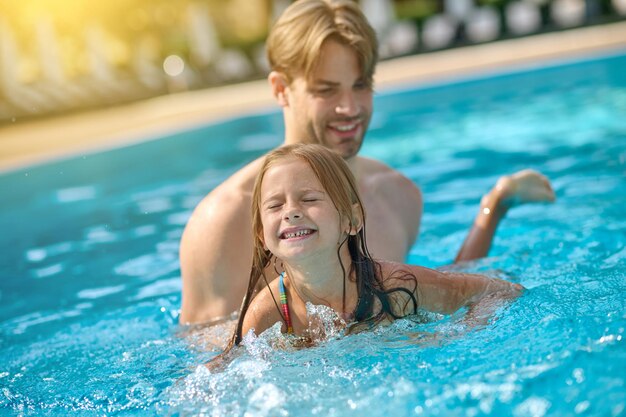 Papá enseñando a su hija a nadar en una piscina