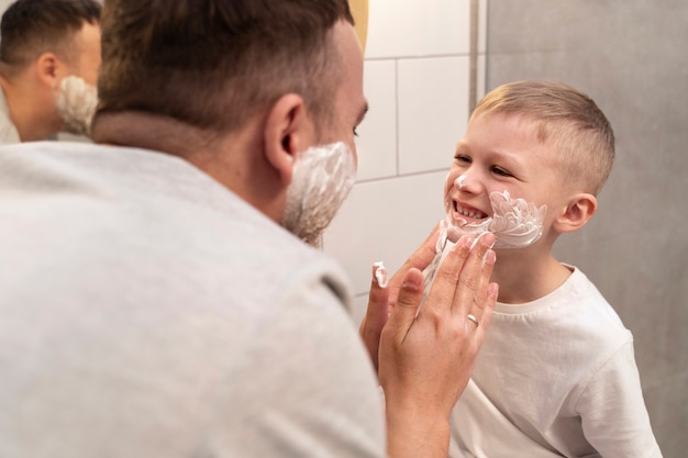 Foto gratuita papá enseñando a su hijo a afeitarse