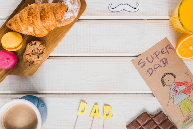 Foto gratuita papá escribiendo cerca de pastelería y dibujo