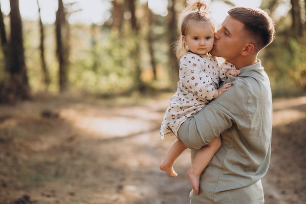 Papá con hija pequeña abrazándose en el bosque