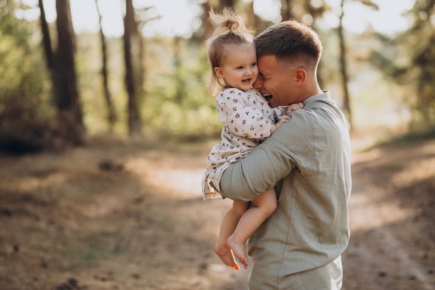 Papá con hija pequeña abrazándose en el bosque