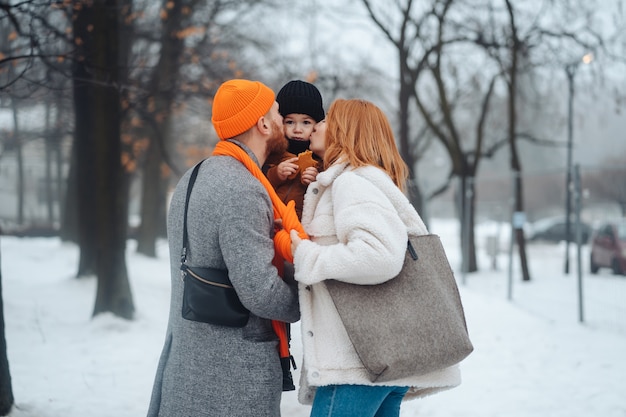 Papá mamá y bebé en el parque en invierno