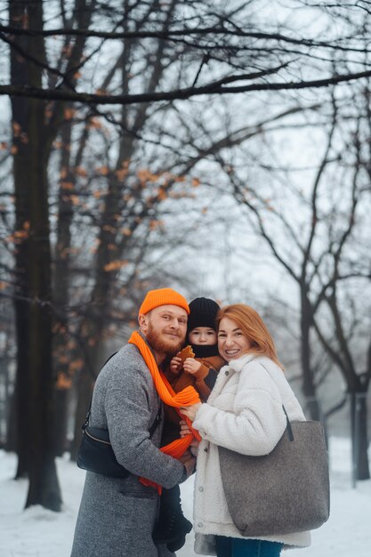 Papá mamá y bebé en el parque en invierno