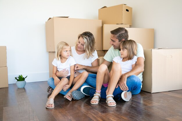 Papá y mamá felices, sentados en el piso, sosteniendo a los niños y sonriendo