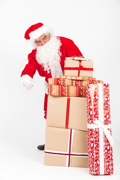 Papá Noel apuntando a la pila de regalos de Navidad