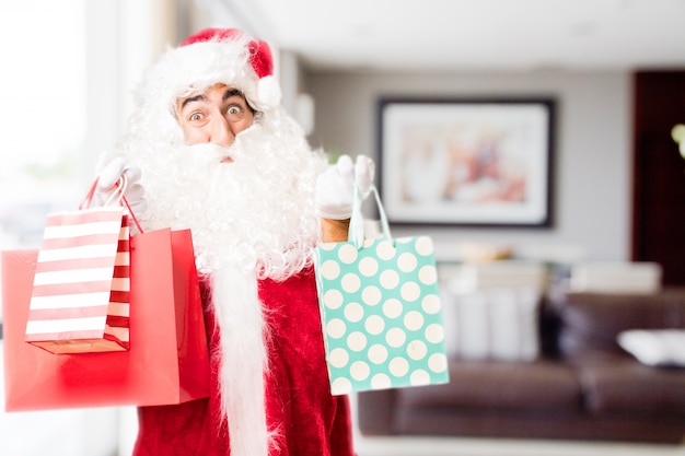 Papa noel con bolsas de la compra en una casa