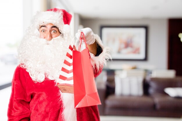 Papa noel con bolsas de la compra rojas