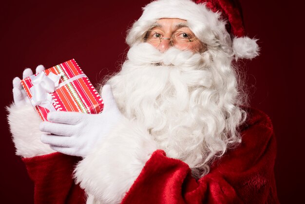 Papá Noel con una caja de regalo sobre fondo rojo.