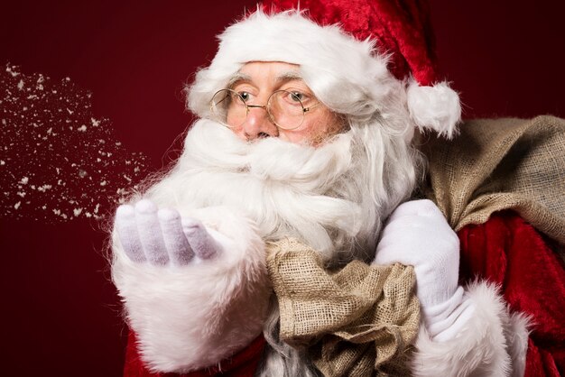 Papá Noel con una caja de regalo sobre fondo rojo.