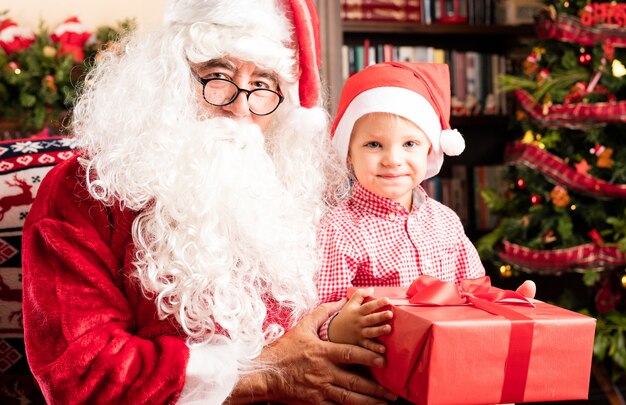 Papa noel entregando un regalo rojo a un niño