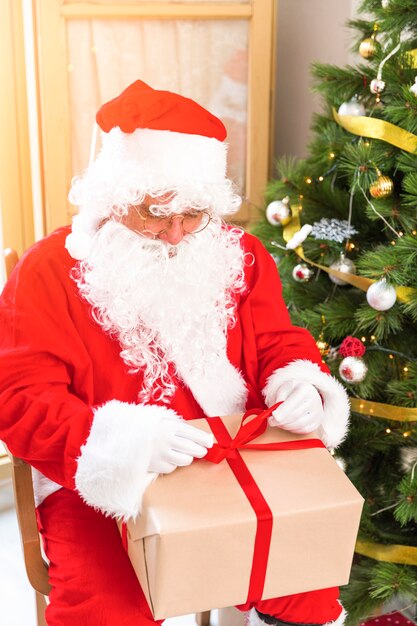 Papá Noel envolviendo regalo con cinta.