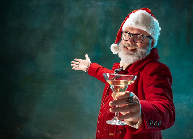 Foto gratuita papá noel con estilo moderno en traje rojo de moda y sombrero de vaquero en la oscuridad