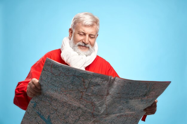 Papá Noel maduro con mapa de papel que planifica el día de Navidad